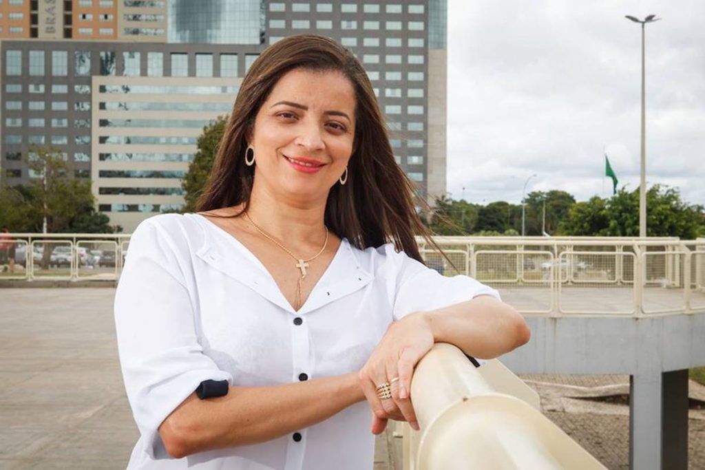 mulher de blusa branca apoiada em corrimão sorrindo