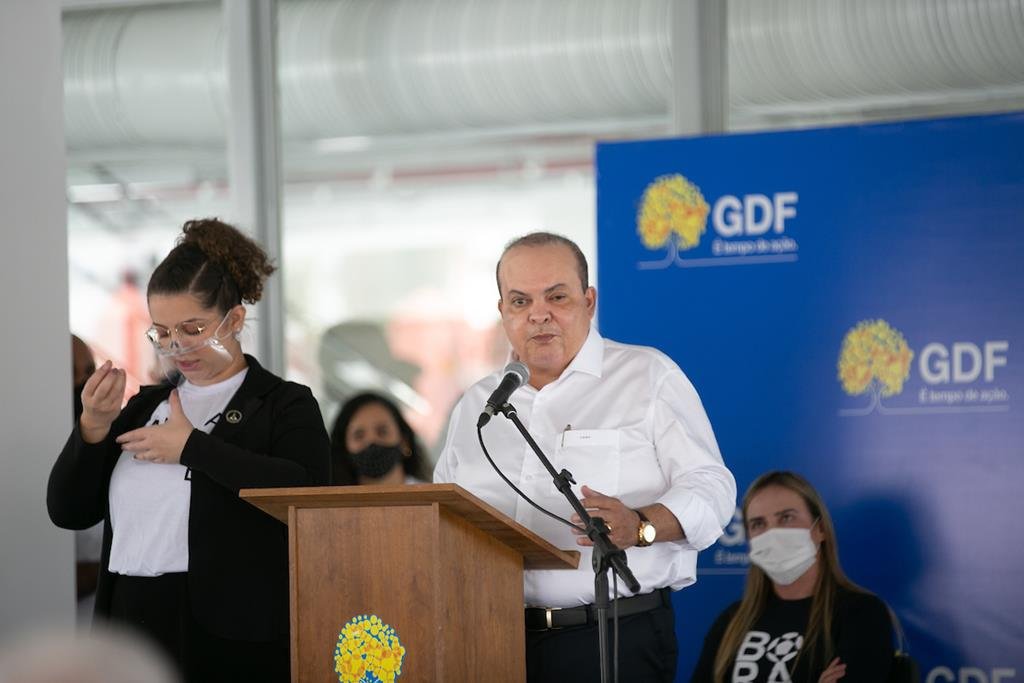 Governador Ibaneis Rocha discursando.  Ele usa blusa branca e calça escura
