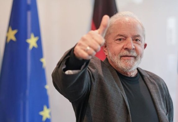 Lula faz sinal de positivo em frente às bandeiras da Alemanha e da União Europeia