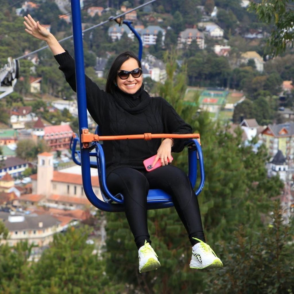Mulher levanta braço sentada m cadeira de teleférico