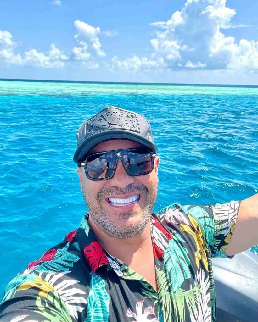 Homem de óculos escuros tira selfie em cima de barco no meio do oceano