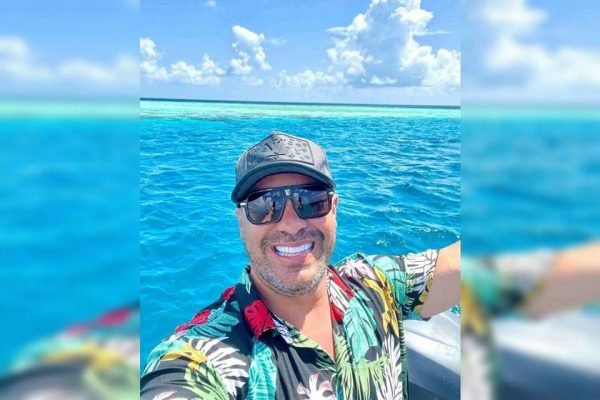 Homem de óculos escuros tira selfie em cima de barco no meio do oceano