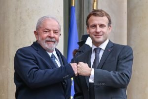 Imagem colorida de Lula cumprimentando o presidente da França, Emmanuel Macron, durante viagem à França