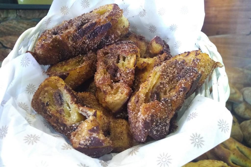 Na fotografia vemos um cesto forrado com papel com a marca da padaria e dentro estão rabanadas feitas com pão de cochocolate