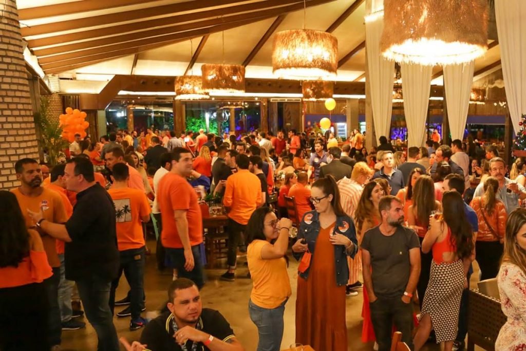 aglomeração de pessoas vestidas de laranja, conversando no que aparenta ser uma festa