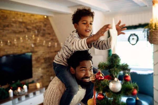 Homem e criança negra montando árvore de natal