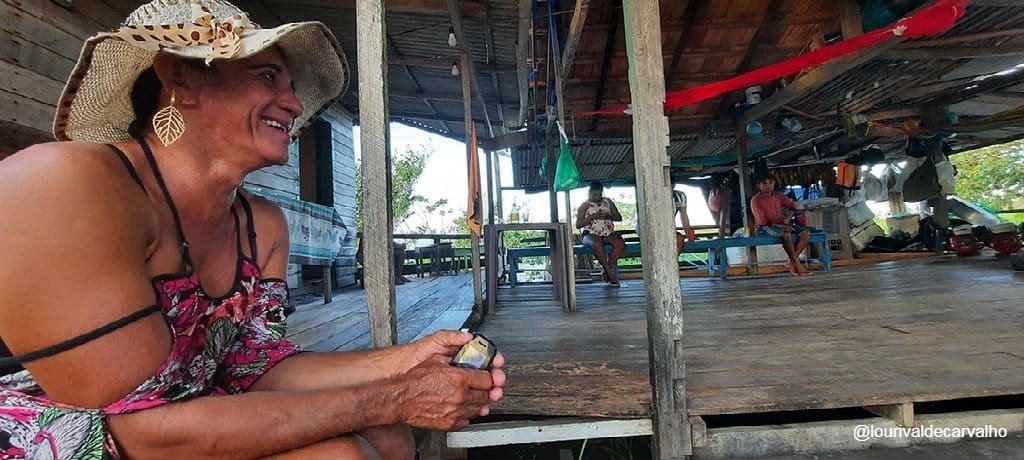 Jade, travesti quilombola sentada em mesa com outros quilombolas