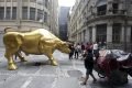 Pessoas tiram selfies com a escultura Touro de Ouro que foi instalada em frente ao prédio da B3 na rua XV de Novembro, no Centro Histórico de São Paulo