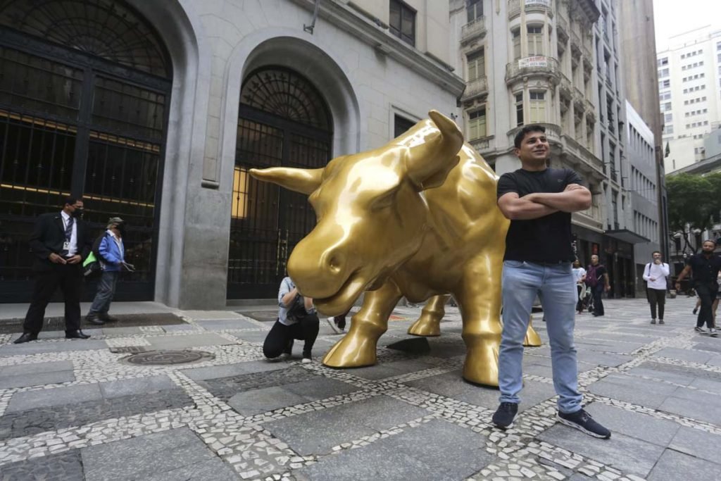 Pessoas tiram selfies com a escultura Touro de Ouro que foi instalada em frente ao prédio da B3 na rua XV de Novembro, no Centro Histórico de São Paulo