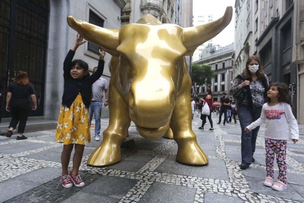 Pessoas tiram selfies com a escultura Touro de Ouro que foi instalada em frente ao prédio da B3 na rua XV de Novembro, no Centro Histórico de São Paulo