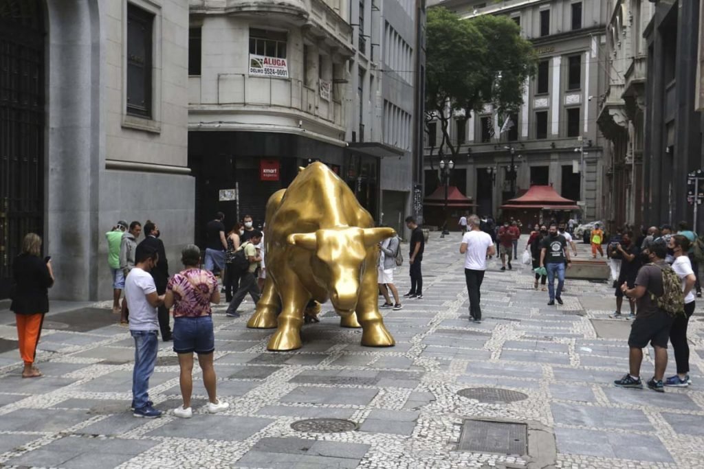 Pessoas tiram selfies com a escultura Touro de Ouro que foi instalada em frente ao prédio da B3 na rua XV de Novembro, no Centro Histórico de São Paulo