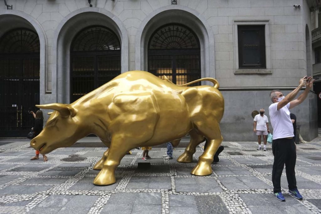 Pessoas tiram selfies com a escultura Touro de Ouro que foi instalada em frente ao prédio da B3 na rua XV de Novembro, no Centro Histórico de São Paulo