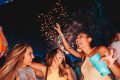 Três jovens mulheres em noite se divertindo com fogos de artifício ao fundo