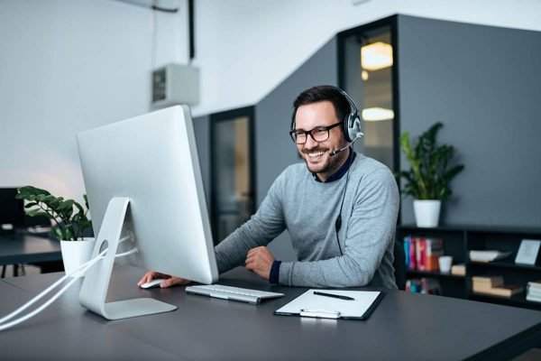 Smiling casual business man with headset working on the computer