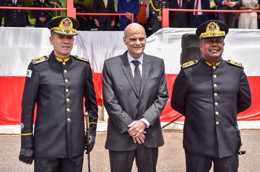 Homens fardados e homem careca de terno e gravata