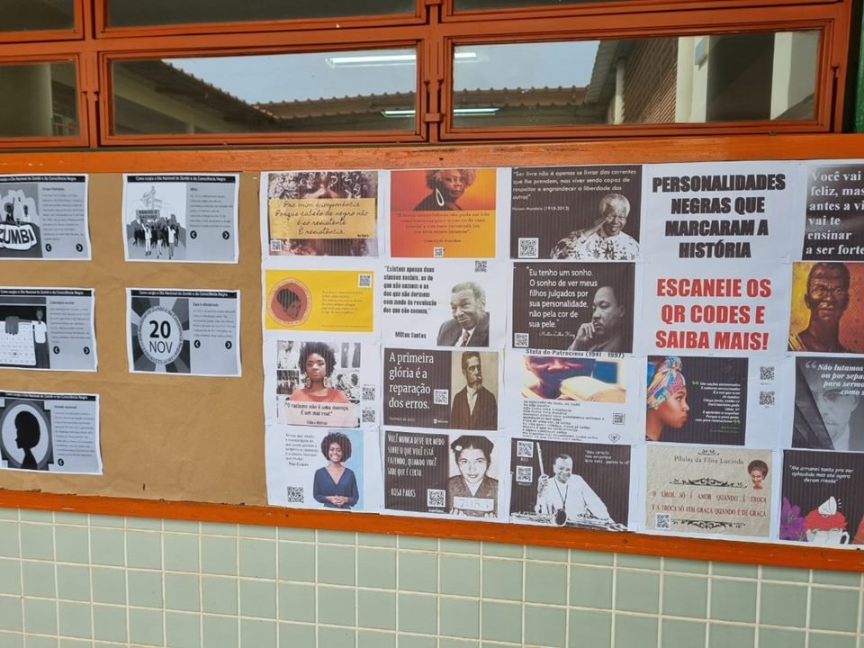 Papeis com rostos de personalidades negras colados em mural