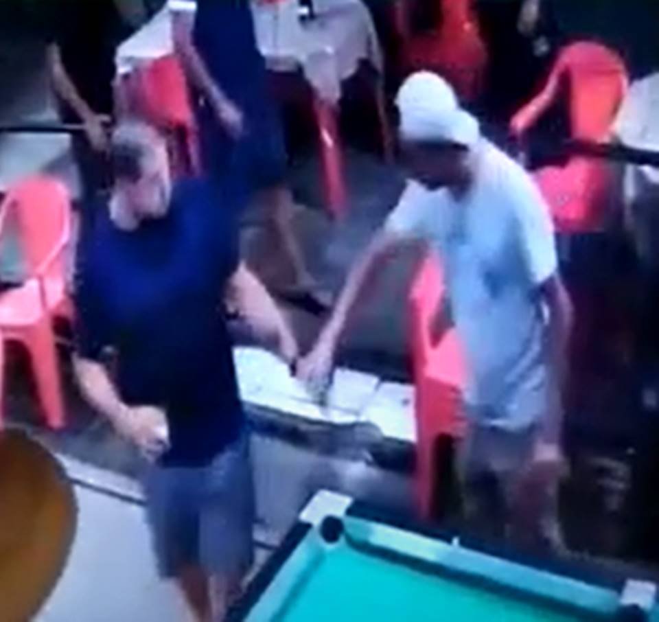 Homem de camisa azul entrega arma para homem de boné