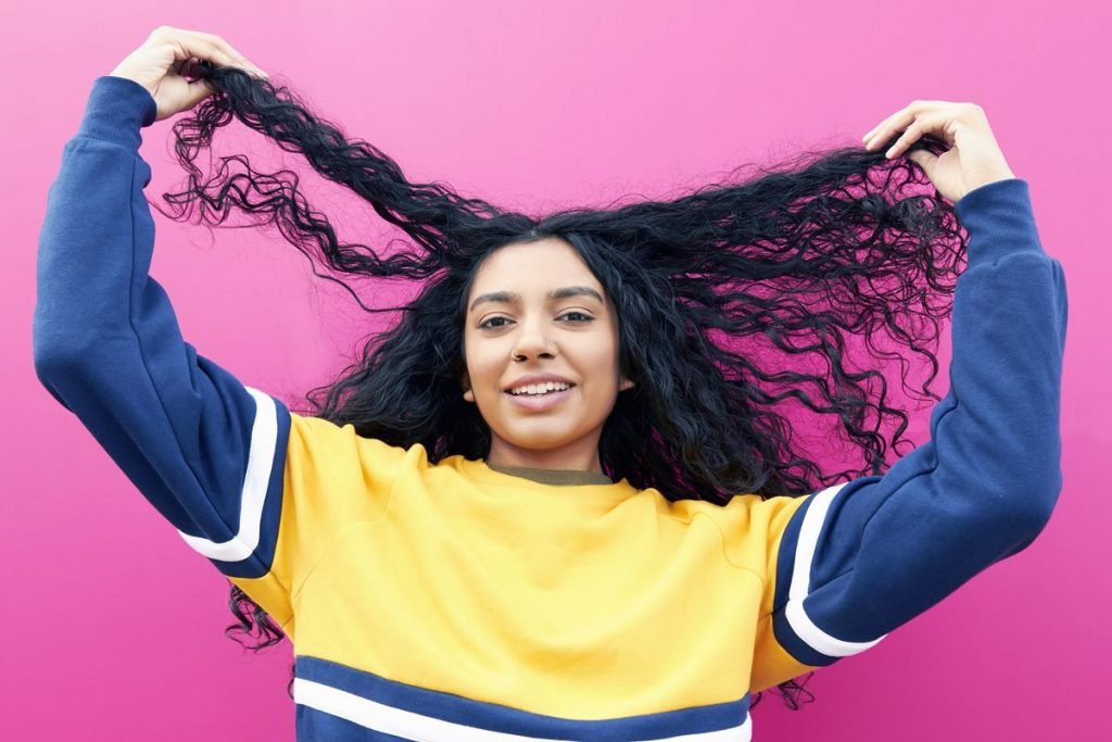 Mulher segura o cabelo cacheado
