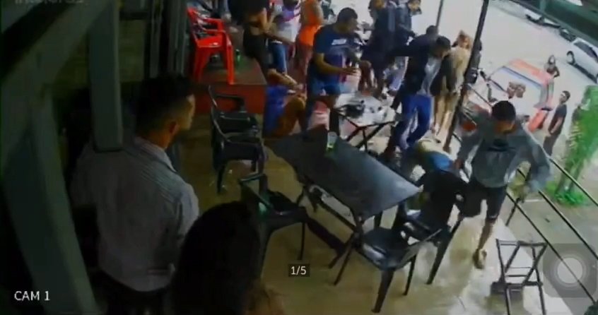 Pessoas brigando perto de mesas e cadeiras