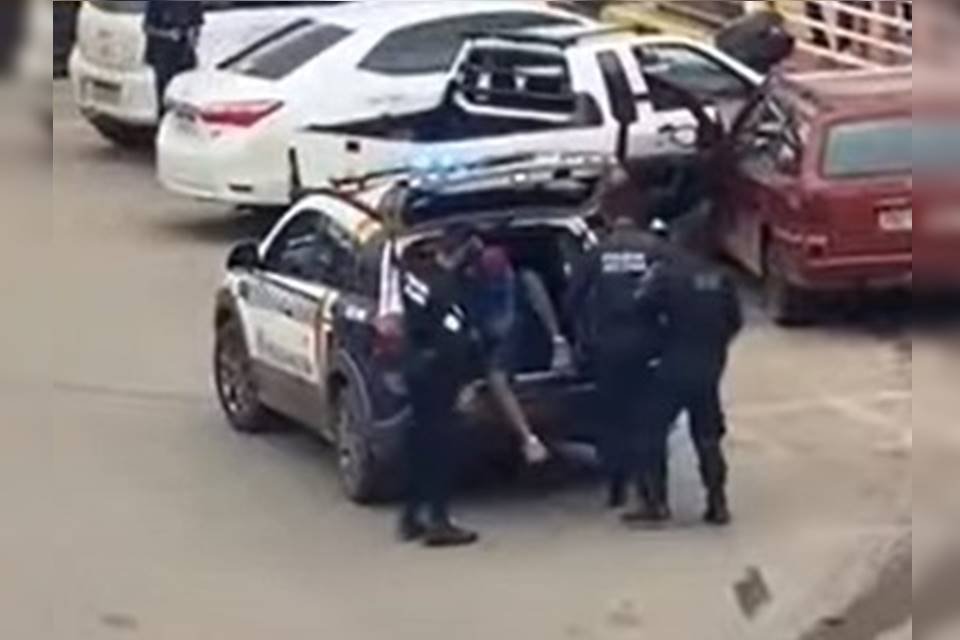 Homem no chão sendo detido por policiais militares de farda azul