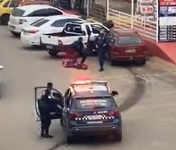 Homem no chão sendo detido por policiais militares de farda azul