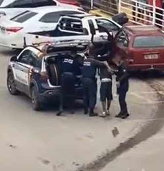 Homem no chão sendo detido por policiais militares de farda azul
