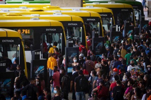 Multidão de pessoas à direita e ônibus amarelos estacionados à esquerda