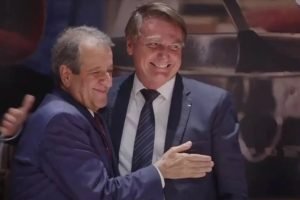 Fotografia colorida. Valdemar (esquerda) e Bolsonaro (direita) se abraçam e sorriem na filiação de Jair ao PL