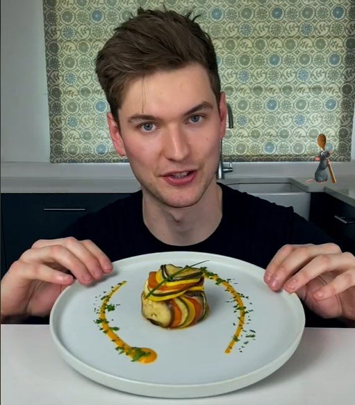 Na foto, um homem branco segura um prato com Ratatouille