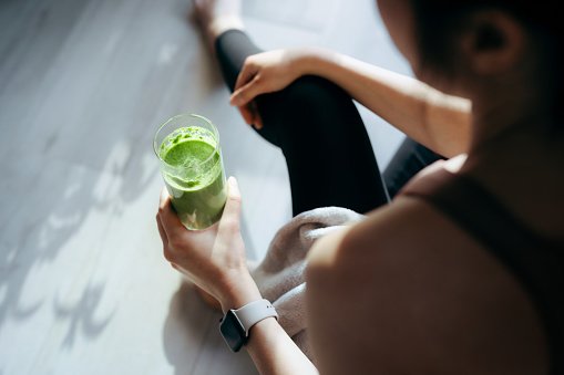 mulher com roupa de academia bebendo suco verde