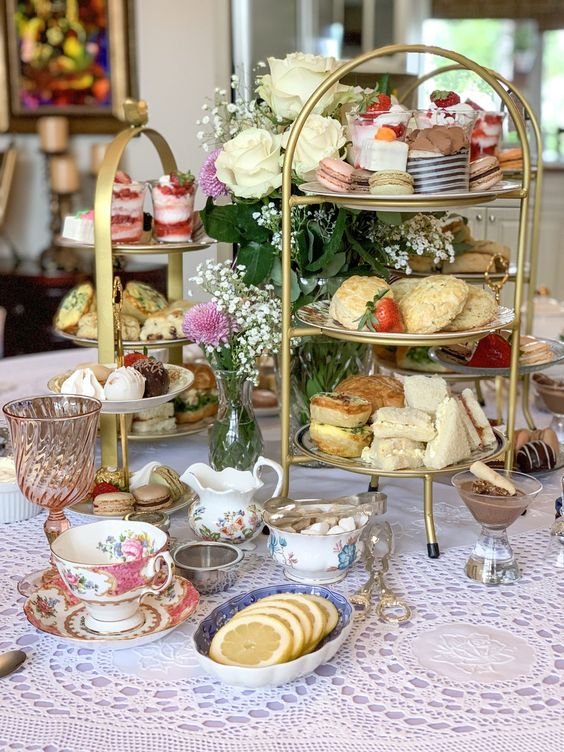 na foto, uma mesa com doces e bules de chá