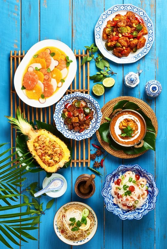 Na foto, várias comidas coloridas em uma mesa azul