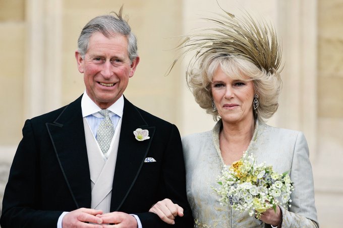 In the color photo, Prince Charles and Camilla smile for a photo at an event