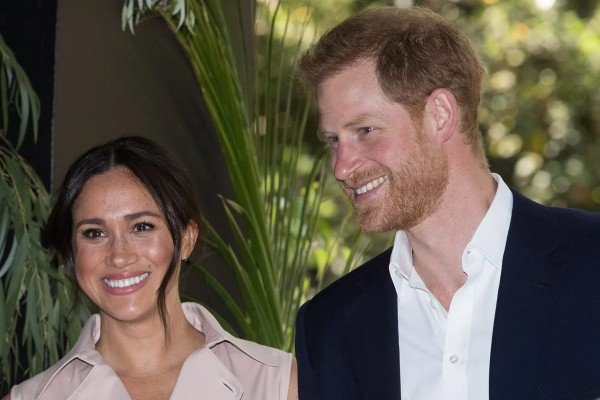 Na fotografia colorida, Meghan Markle e príncipe Harry posam para foto sorrindo