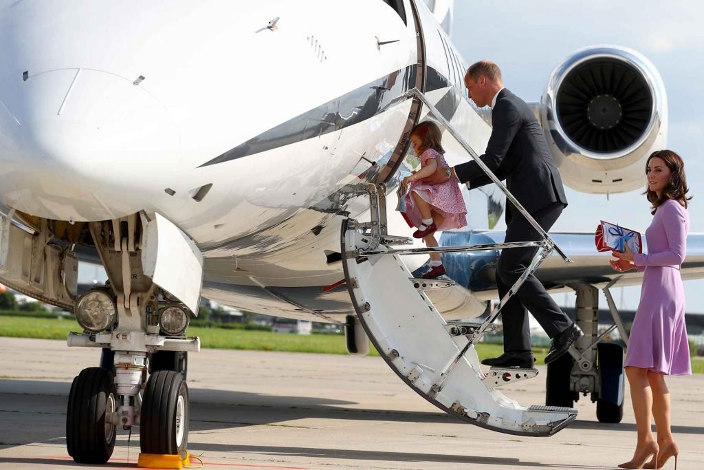 Na fotografia colorida, três membros da família real aparecem embarcando no avião