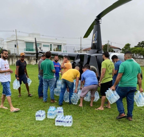 pessoas retiram garrafas de água do helicóptero