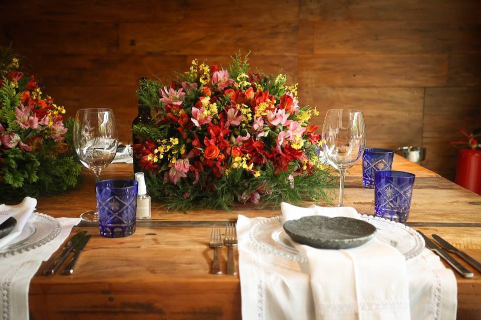 Mesa com pratos, copos e arranjos de plantas