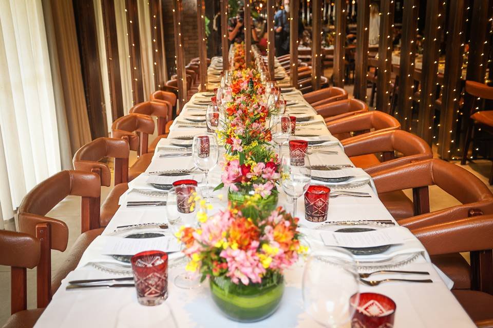 Mesa com pratos, copos e arranjos de flores