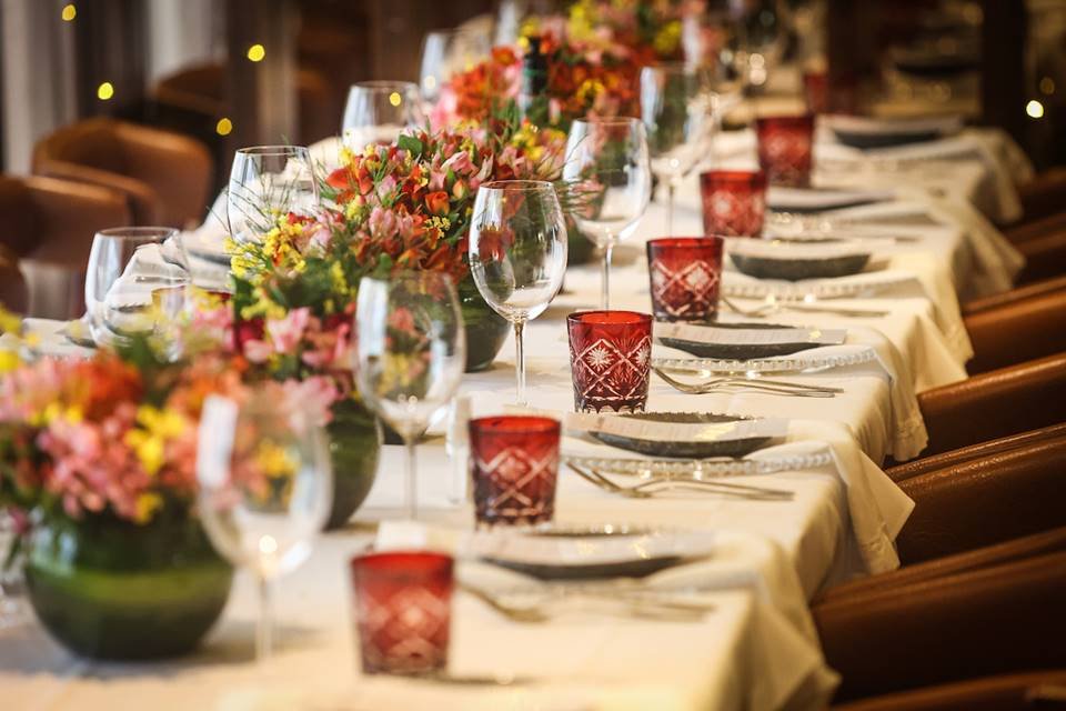 Mesa com pratos, copos e arranjos de flores