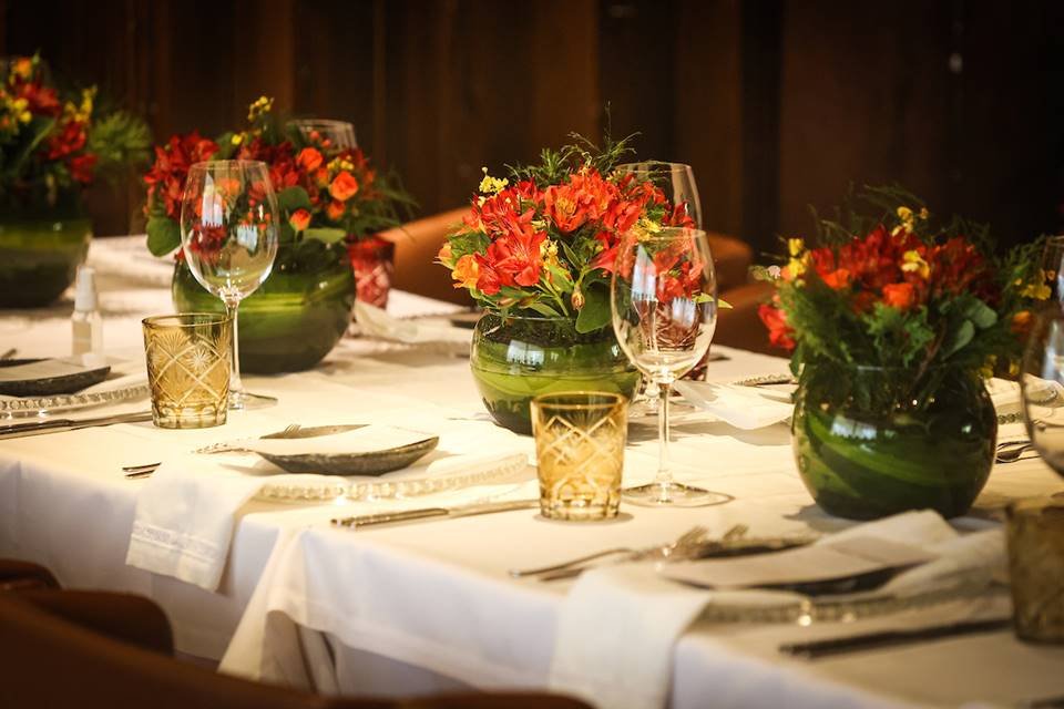 Mesa com pratos, copos e arranjos de plantas