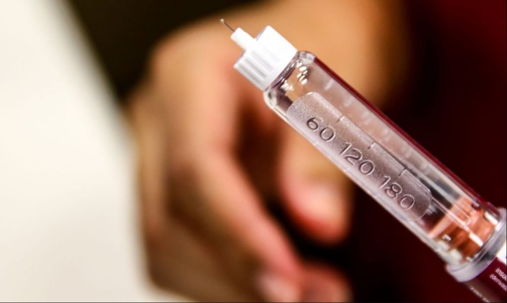 Na imagem colorida, uma seringa com insulina está em evidência