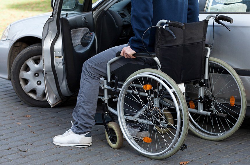 Pessoa sentada em cadeira de rodas entrando em carro