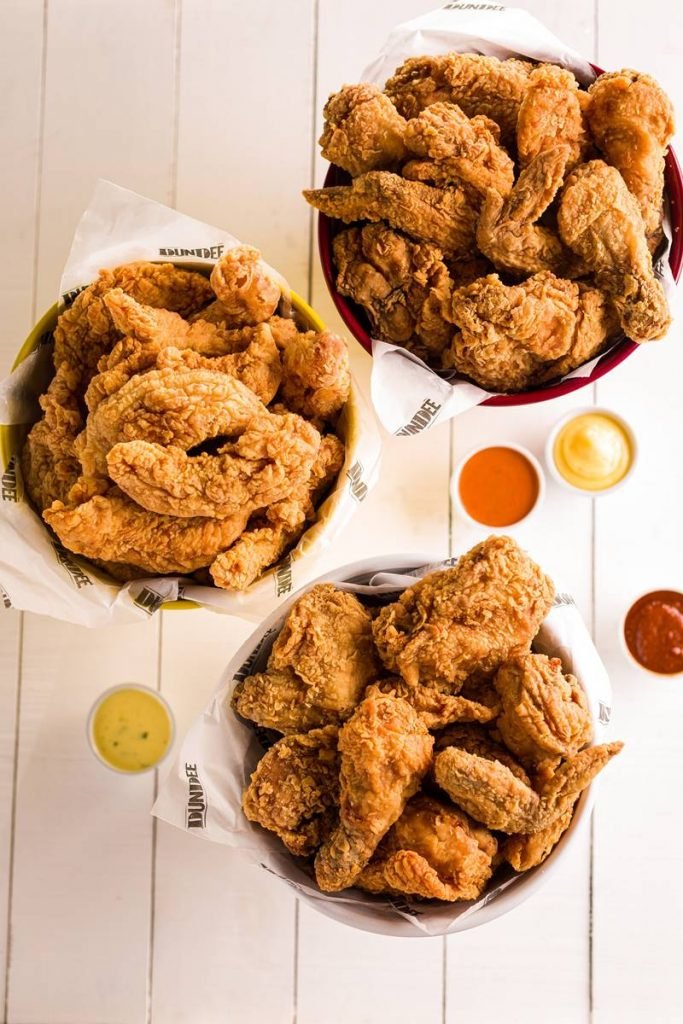 Na foto, um balde de frango frito com molhos