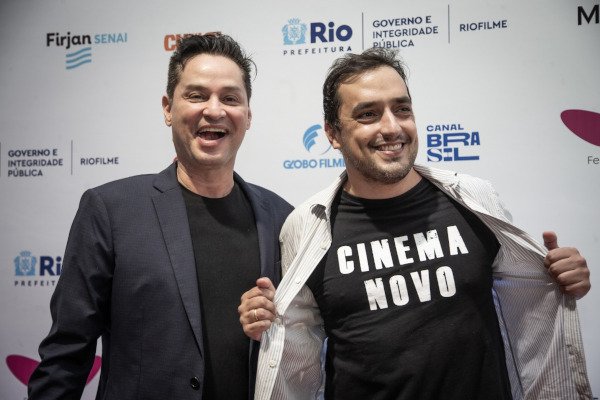 dois homens, um deles exibe camiseta onde se lê 'cinema novo'