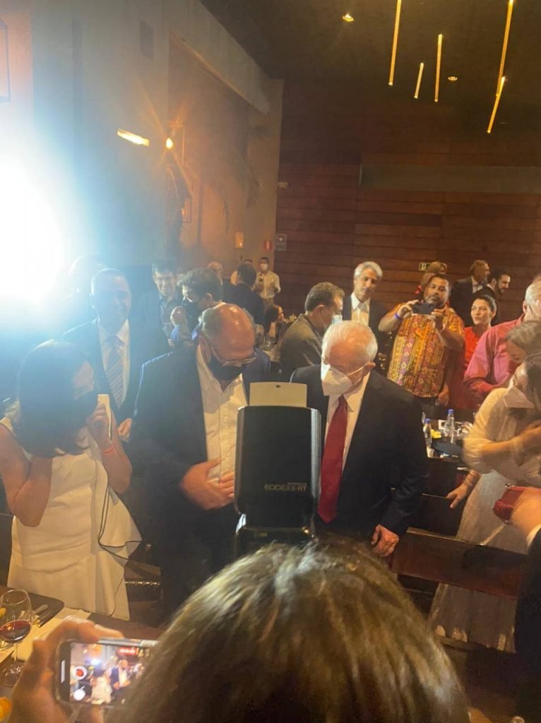 Em jantar em São Paulo, Alckmin e Lula se reúnem com aliados e entusiastas de uma possível aliança. Eles tiram foto no restaurante cheio, acompanhados por suas esposas. Ambos usam terno e conversam - Metrópoles
