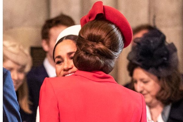 Fotografia colorida. Kate e Meghan sorriem e se abraçam