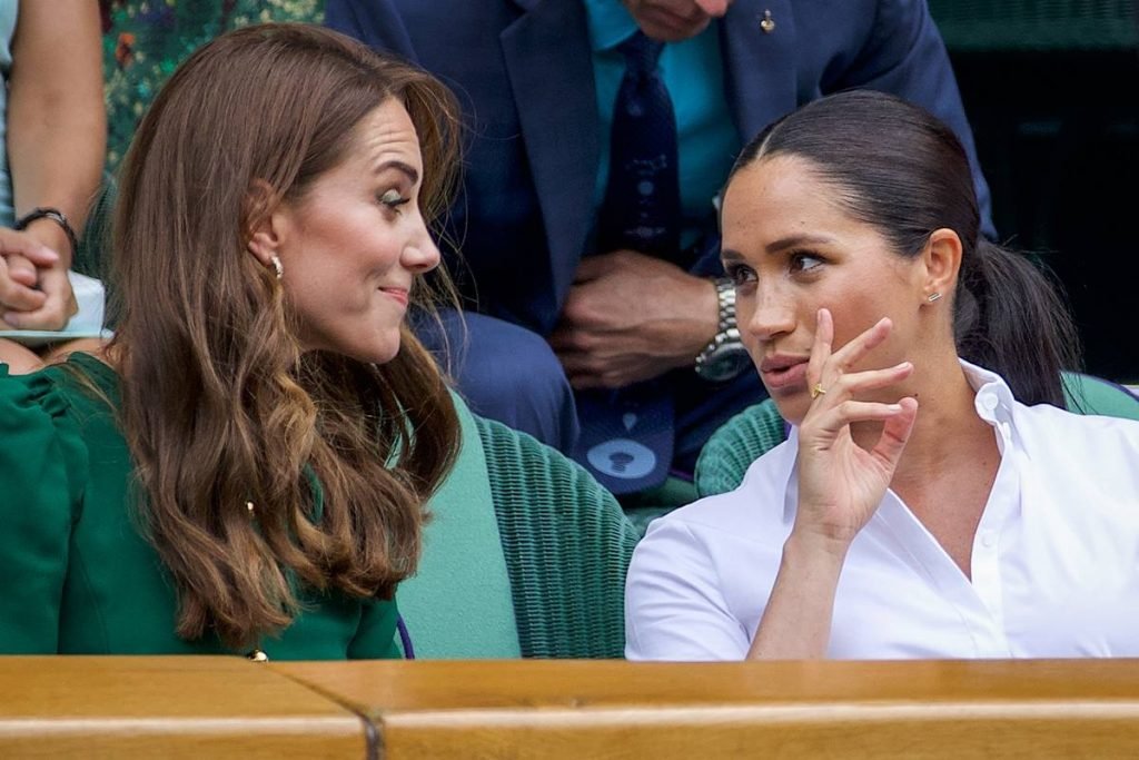 Fotografia colorida. Kate Middleton e Meghan Markle conversam em evento