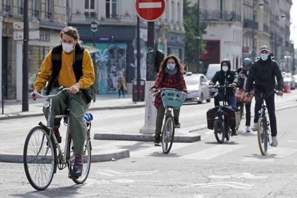 pessoas andando de bicicleta e de máscara, colorida
