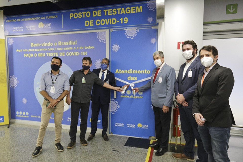 Homens de terno segurando faixa em frente a parede azul