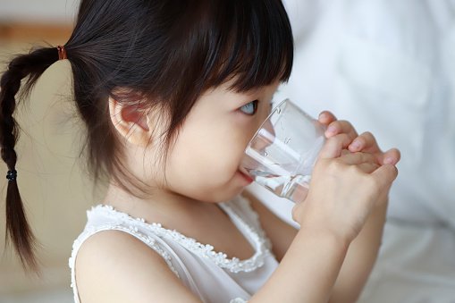 Bebê asiática bebendo um copo de água
